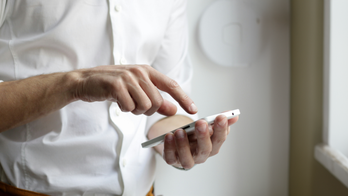 Perdendo uma ligação do seu chefe.  Uma pessoa de camisa branca usa um smartphone tocando na tela com o dedo.